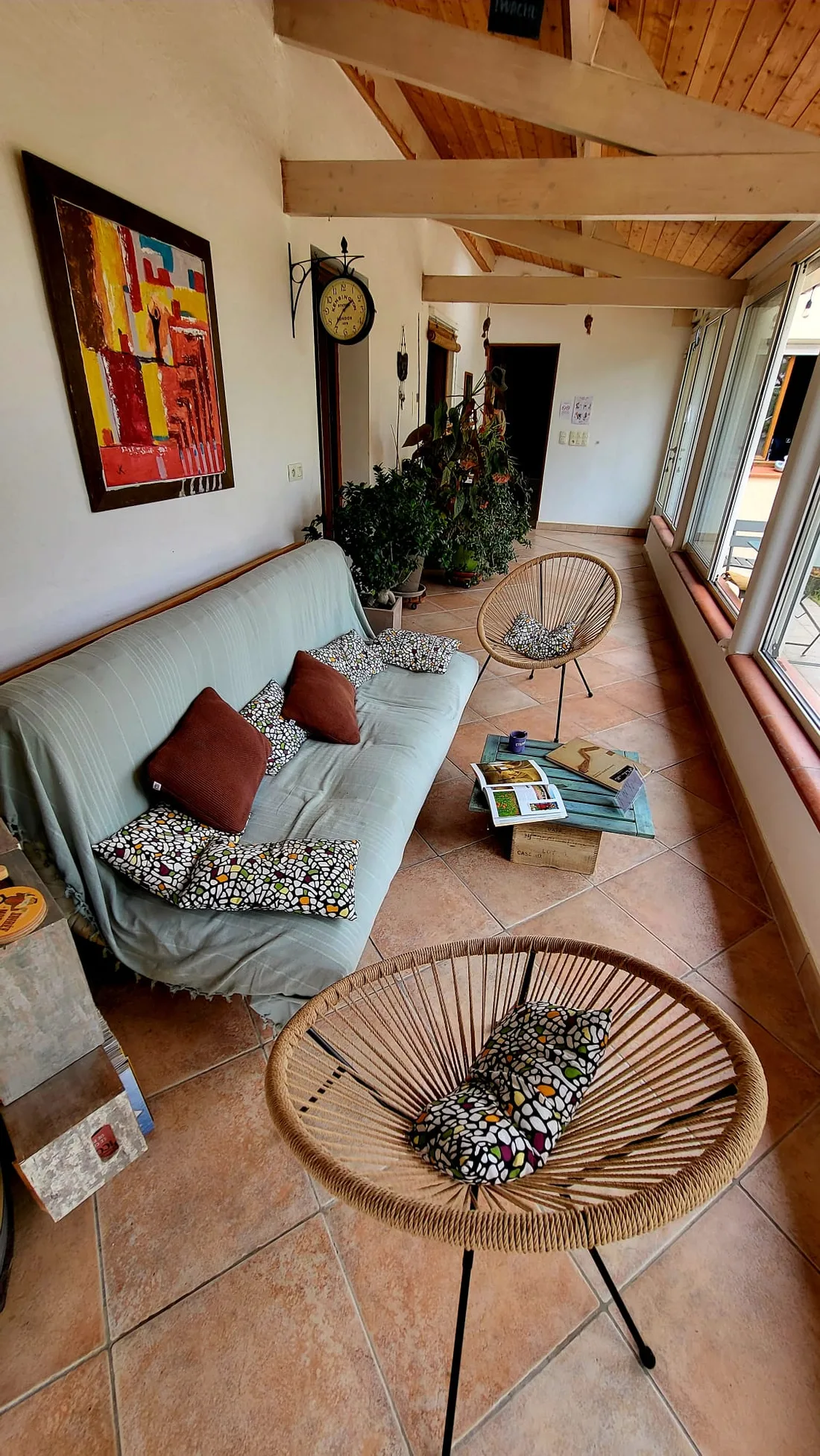 Véranda lumineuse avec canapé, fauteuils et table basse